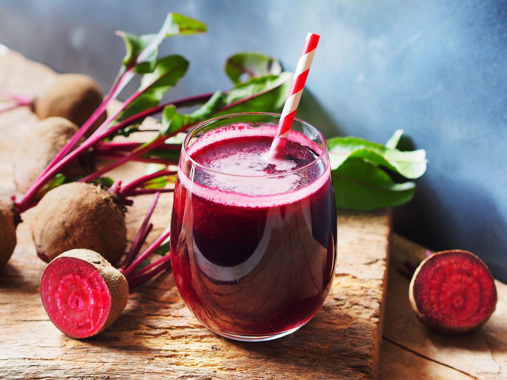 Beetroot juice in a glass and fresh organics beetroot on rustic wooden table for refreshing drinks concept.