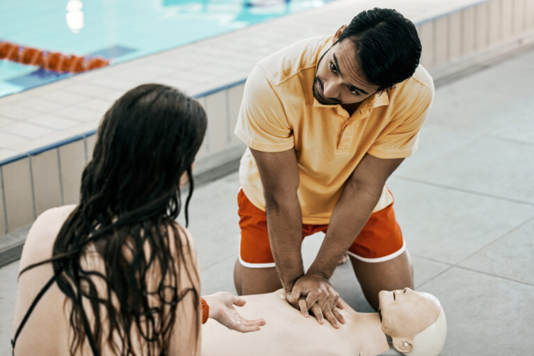 Swimming pool lifeguard, first aid and man teaching life saving process rescue support or helping with danger. Client, emergency CPR and person learning medical service, safety or practice on dummy