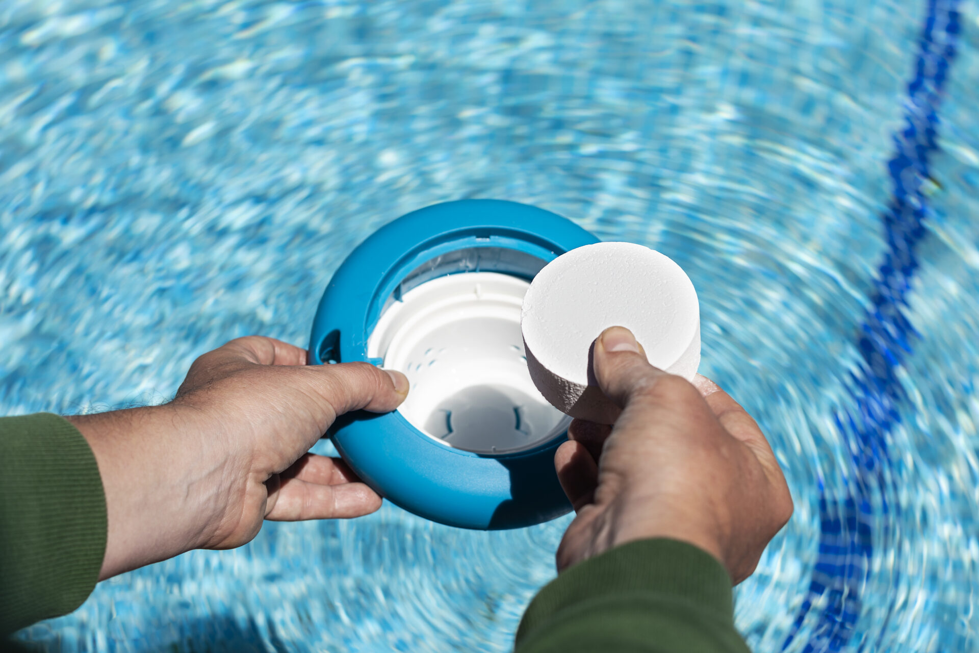 Operator's hand introducing white chlorine tablets on the pool skimmer. Chlorine tablets for pool water. disinfection and prevention against the development of microbes with chlorine