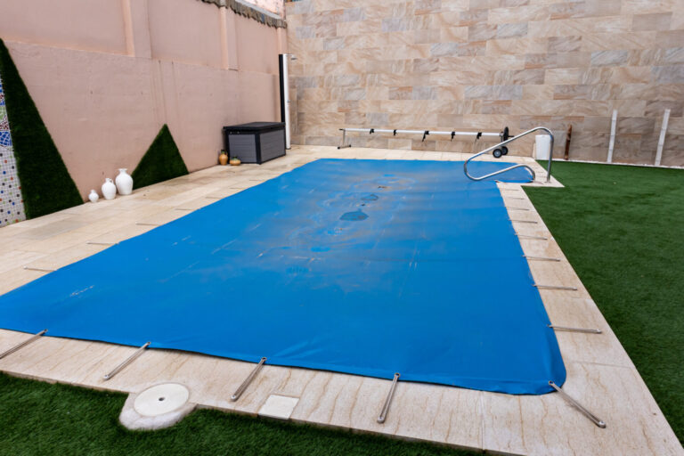Small pool covered with a blue tarpaulin during the winter season to cover it and prevent dirt and objects from entering the water.